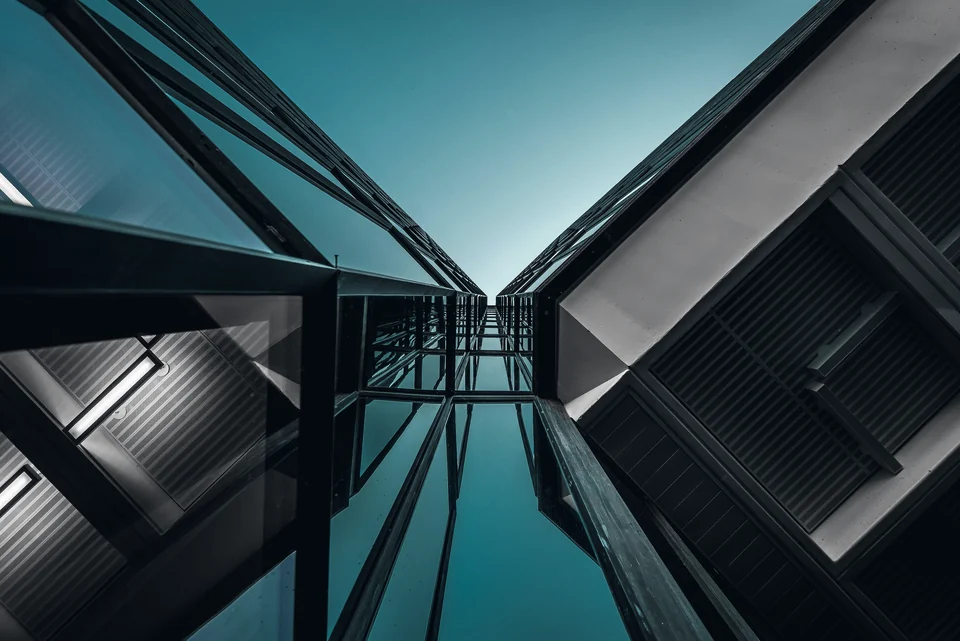 The glass facades of two towers, seen from below