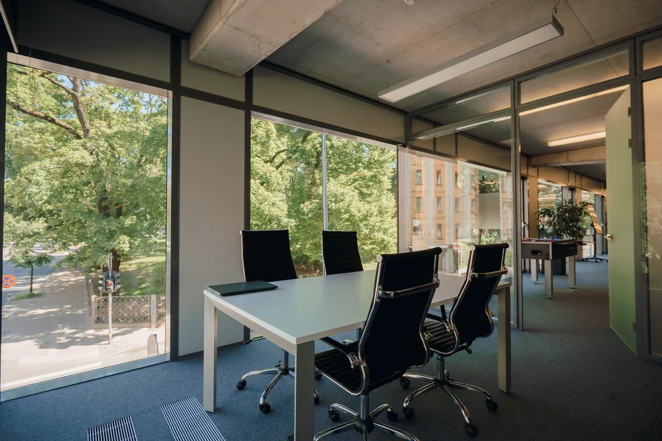 A meeting room with a wall of windows onto trees